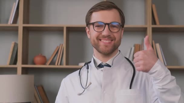 カメラで親指を立てて微笑む前向きな男性医師のポートレート 高品質4Kビデオ — ストック動画