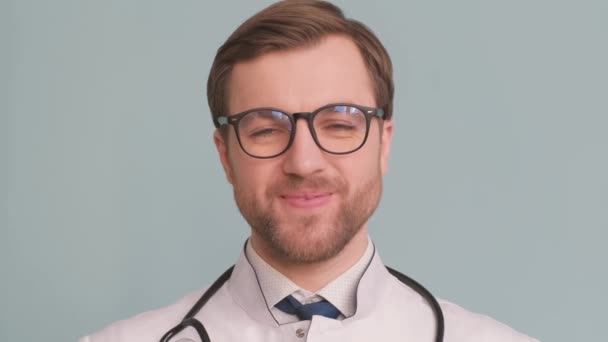 眼鏡をかけた若い医師のクローズアップ肖像画 彼はカメラのレンズを見て笑っている 人々を治療するという概念 — ストック動画
