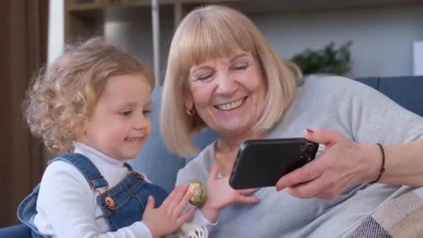 Szczęśliwa Babcia Spędza Czas Wnuczką Domu Oglądają Kreskówki Smartfonie Wideo — Wideo stockowe