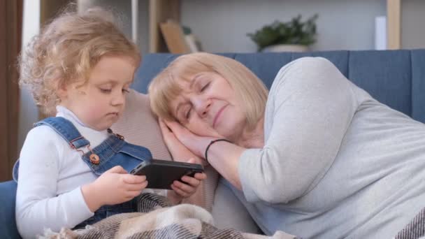 Una Niña Está Jugando Con Smartphone Mientras Abuela Duerme Adicción — Vídeo de stock
