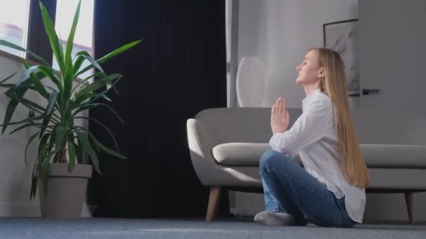 Genç Bir Sarışın Oturma Odasının Ortasında Lotus Pozisyonunda Yoga Yapıyor — Stok video