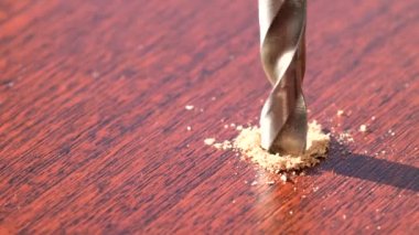 Ahşap parlak bir yüzey üzerinde çentikler açan metal matkabın yakın plan görüntüsü. Sanayi üretiminde, atölyede ahşap ile çalışmak