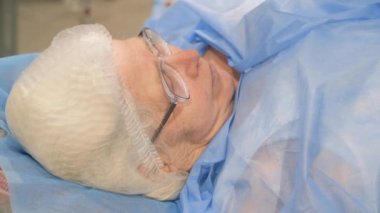Hastanedeki bir yatakta yatan yaşlı bir kadının portresi. Modern bir klinikte tedavi gören bir hasta.