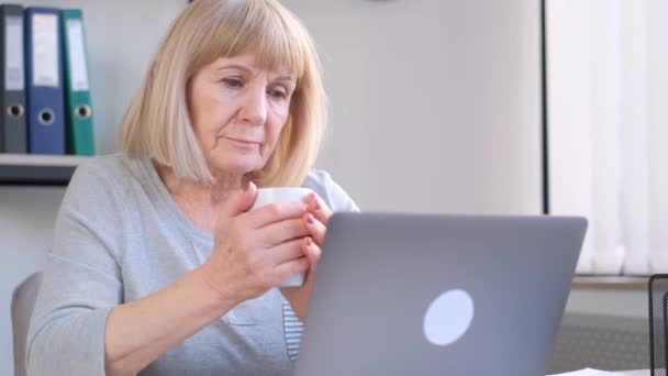 祖母通过视频链接与人交流 手里拿着一大杯茶 在老年时期使用现代技术 — 图库视频影像