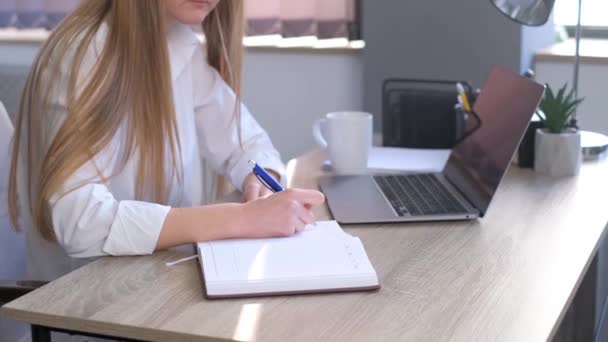一位女办公室经理在笔记本上写下了一个业务计划 办公室里的女员工坐在笔记本电脑旁 4K视频 — 图库视频影像