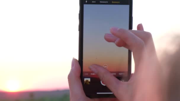 女性がスマホで美しい夕日を撮影しています 4Kビデオ — ストック動画