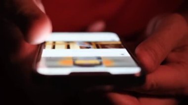 Akıllı telefonlu bir adamın elinin yakın çekimi. Bir adam internette haberleri izliyor.