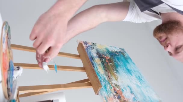 一个专业画家用画笔和画架在白色画布上画画的垂直视频 艺术家创作一幅画的过程 — 图库视频影像