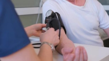 Terapist bir erkek hastanın kan basıncını ölçer. Yaşlı bir adamda tansiyon ve kalp sorunları. Yüksek kalite 4k video