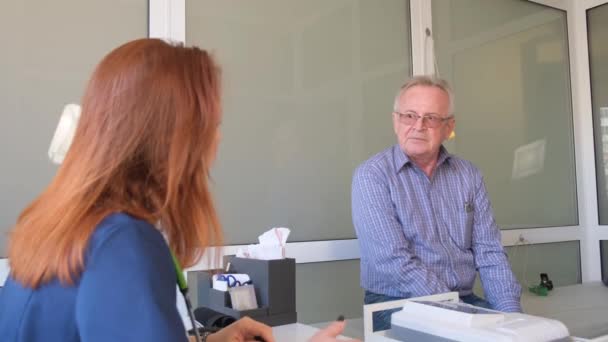 Una Doctora Sienta Escritorio Habla Con Paciente Anciano Mientras Observa — Vídeos de Stock