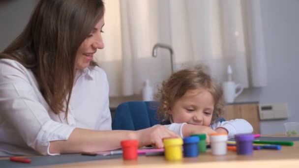 Мать Учит Свою Дочь Рисовать Цветными Красками Сидя Кухонным Столом — стоковое видео