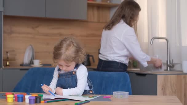 Mała Dziewczynka Dużą Ilością Kolorowych Ołówków Koloruje Obraz Książce Kuchni — Wideo stockowe