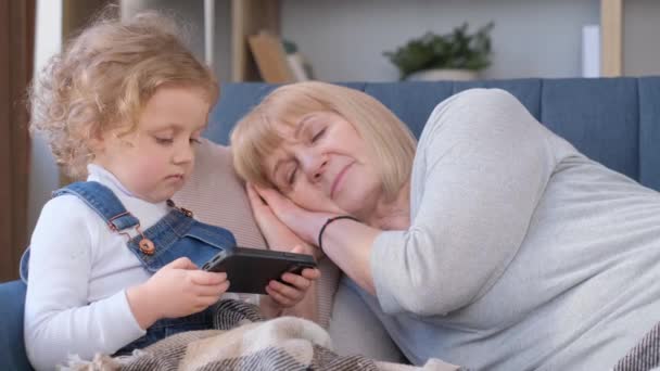 Mała Dziewczynka Bawi Się Smartfonem Kiedy Jej Babcia Śpi Uzależnienie — Wideo stockowe