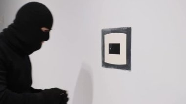 Siyah maskeli bir erkek yankesici alet kullanarak bir apartman kasasını açıyor. Kanunun ihlali.