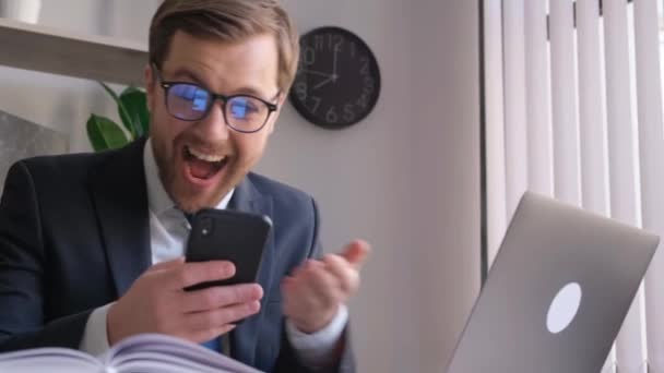 在办公室里拿着智能手机的疯狂商人 他感到快乐和精力充沛 快乐的上班族 兴高采烈 — 图库视频影像