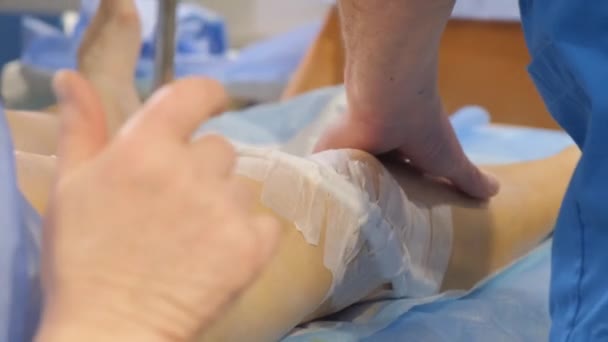 手術後に患者の足の静脈を調べる外科医のクローズアップ 滅菌手袋の外科医の手の静脈瘤 — ストック動画