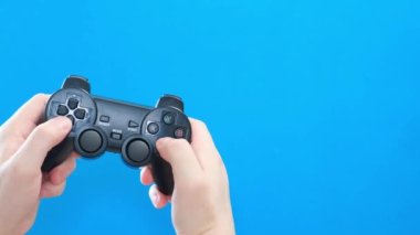 Genç bir adam mavi ekran arka planında joystick ile oynar. Mavi kromakey. Bilgisayar oynatıcı