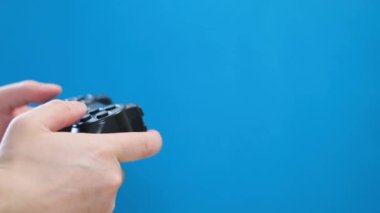 Genç bir adam mavi ekran arka planında joystick ile oynar. Mavi kromakey. Bilgisayar oynatıcı