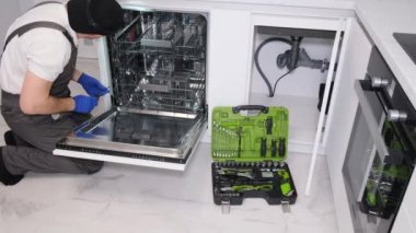 Bulaşık makinelerinin tamiri. Usta eve geldi ve bulaşık makinesini tamir ediyor..