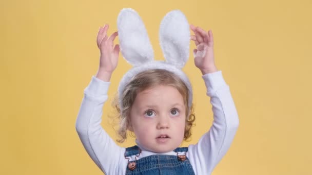 复活节 春天的概念 可爱的小女孩 戴着黄色背景的兔子耳朵帽带 — 图库视频影像
