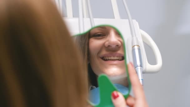 在牙科诊所里欣赏微笑的女人 快乐的年轻女性微笑着检查她完美的牙齿健康在镜子中的特写 — 图库视频影像