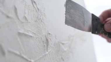 Profesyonel bir sanatçı beyaz bir tuvale metal bir fırça ve sehpa kullanarak resim çizer. Bir sanatçının alçıdan bir resim yapma süreci.
