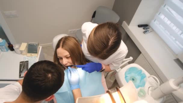 两名牙医在牙科诊所为一名女病人服务在现代诊所接受无痛的牙科治疗 4K视频 — 图库视频影像