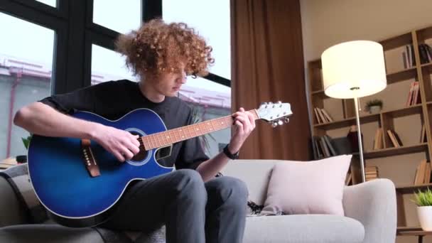 一个男音乐家会弹蓝色的声吉他 现代年轻的嬉皮士吉他手弹吉他 花哨的卷发 — 图库视频影像