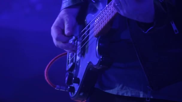 仮面の男はクラブのロック コンサートでエレキ ベースのギターを演奏する 大都市でのナイトライフ 赤と青の照明 — ストック動画