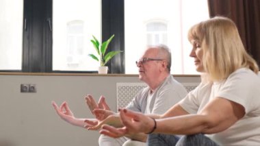 Mutlu yaşlı çift evde fitness yogası yapıyor. Olgun emekli karı koca meditasyonun tadını çıkarıyor. Sağlıklı yaşam tarzı kavramı