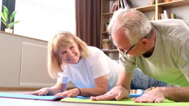 笑顔祖父母は自宅で健康体操をしています 高齢者のための健康的なライフスタイル プランク運動 — ストック動画