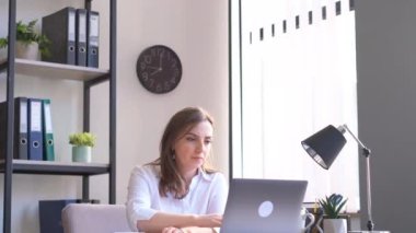 Ofiste çalışan genç bayan ofis müdürü. Ofiste çalışan kadın dizüstü bilgisayarın başında oturuyor. 4k video