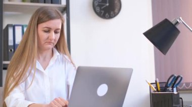 Ofis müdürü kız bir dizüstü bilgisayarda çalışıyor ve başka tarafa bakıyor. Ofiste çalışan bir iş kadını..
