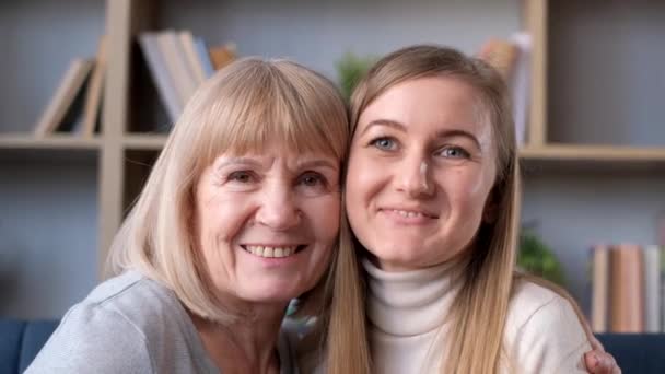 一个漂亮的金发姑娘和她妈妈的画像 他们看着相机笑着 快乐的家庭在家里休息 — 图库视频影像