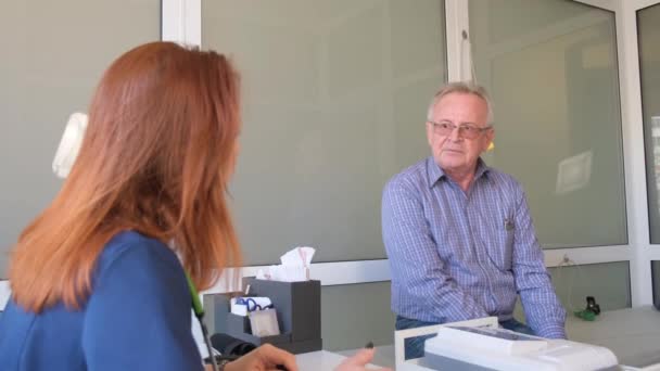 Una Doctora Sienta Escritorio Habla Con Paciente Anciano Mientras Observa — Vídeo de stock