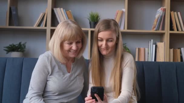 Una Hermosa Rubia Con Madre Está Mirando Teléfono Inteligente Sonriendo — Vídeo de stock