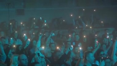 Büyük salondaki müzik festivalinde bir hayran kitlesi akıllı telefonlarını parlatıyor. Caz konseri. Ukrayna, Ternopil, 20 Mart 2023