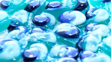 Bir grup mavi çamaşır kapsülünün daireler çizerek döndüğü görüntüyü yakınlaştır. Çamaşır makinesinde yüksek kaliteli çamaşır yıkama aracı.
