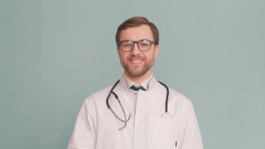 Erkek doktor hapları gösteriyor ve atıyor. Stüdyodaki gri arka planda izole halde. Antibiyotiklerle tedavi. 4k video