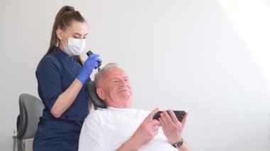 Kadın doktor trikoloğu, saç uzaması için klinikte kel ve olgun bir adamı tedavi ediyor. Erkeklerin kelliği için yaşlanma karşıtı tedavi uyguluyor. Saç nakli prosedürleri konsepti. 4k video