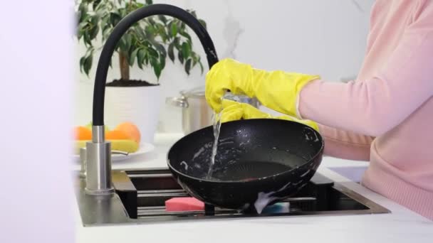 一个戴黄色手套的女人在一个现代的白色厨房里洗盘子 家庭的清洁 — 图库视频影像