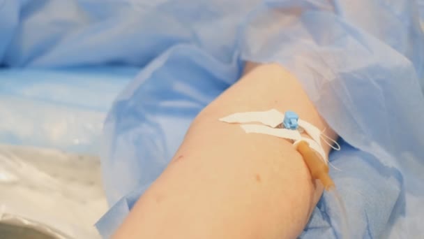 ドリップカテーテルで手術室に横になっている患者の腕のクローズアップ 手術の概念 — ストック動画