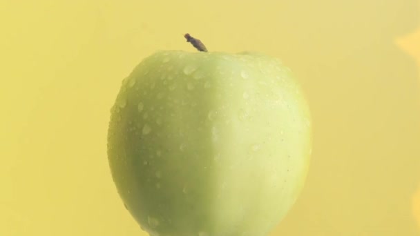 一个伟大的视频一个绿色的苹果在黄色的背景旋转在盘子上 招贴画用水果宏观视频 — 图库视频影像