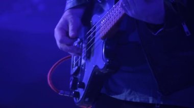 Maskeli bir adam bir kulüpteki rock konserinde elektro bas gitar çalar. Büyük bir şehirde gece hayatı. Kırmızı ve mavi ışık