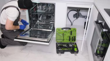 Bulaşık makinelerinin tamiri. Usta eve geldi ve bulaşık makinesini tamir ediyor..