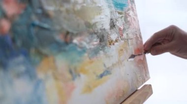 İş ceketli bir sanatçı, beyaz bir tuvale fırçalarla resim yapan bir video blogunu kaydeder. Atölyede yağlı boya resim yapma süreci. Şövaleye resim çiziyorum.