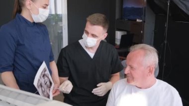 Profesyonel dişçi yaşlı hastasıyla çalışıyor, dişçiyi ziyaret eden yaşlı bir adam klinikteki dişleri, dişçiliği, sağlık hizmetlerini, insan sigortasını inceliyor. Yüksek kalite 4k video