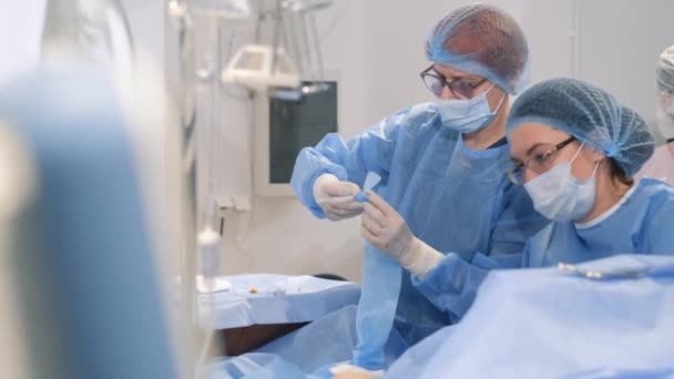 女性外科医が帝王切開を行う アシスタントと一緒に防護服の医者は滅菌装置を使用して操作を行います — ストック動画