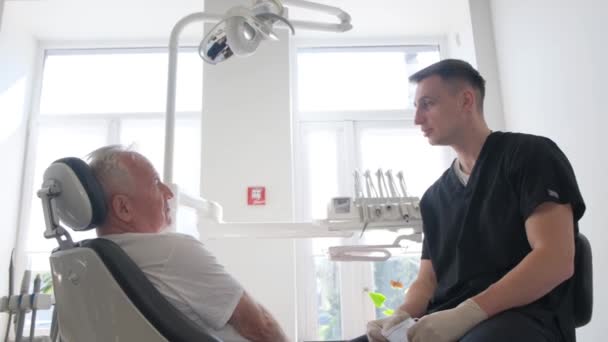 Красивый Старик Разговаривающий Дендистом Два Человека Кабинете Дантиста Стоматолог Осматривает — стоковое видео