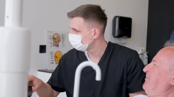 Ein Grauhaariger Rentner Sitzt Auf Einem Zahnarztstuhl Und Erzählt Von — Stockvideo